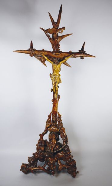  Important crucifix, la base formée de racines entremêlées d'où surgit un serpent,...
