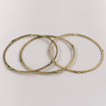null Three rigid BRACELETS in yellow gold (750‰) finely guilloché. Broken. French...