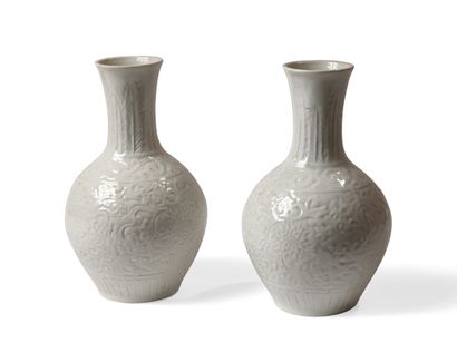null A pair of white porcelain baluster vases decorated in light relief with palm...