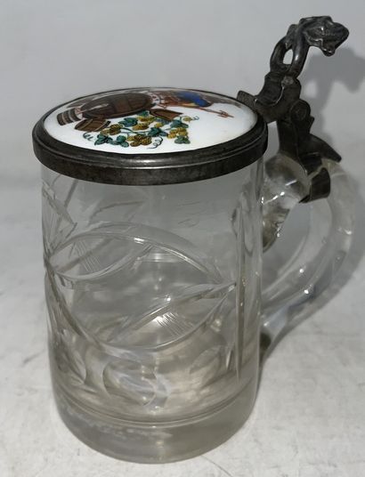 null Lot of two mugs including:

- cut glass mug, pewter lid decorated with a porcelain...