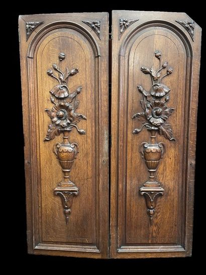 null Deux portes en chêne naturel mouluré et sculpté à décor de vases fleuris posant...