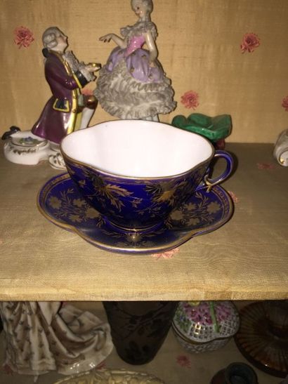null Tasse et sous-tasse polylobées en porcelaine à décor or de fleurs sur fond bleu,...