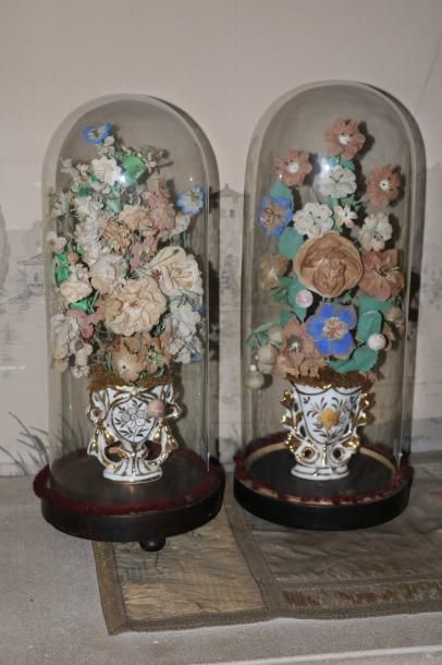 null Deux bouquets en composition, chacun sous un globe en verre, vases en porcelaine...