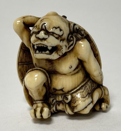 null JAPON, XIXe. NETSUKE en ivoire, oni se protégeant de l'oni yarai derrière un...