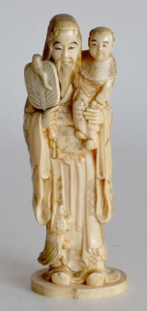 null OKIMONO en ivoire sculpté, sage tenant un éventail et enfant. Japon fin XIXe....