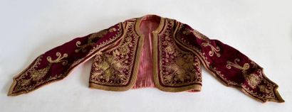 null VESTE d'ENFANT en velours rouge brodé de fils d'or à décor de rinceaux. XIX...