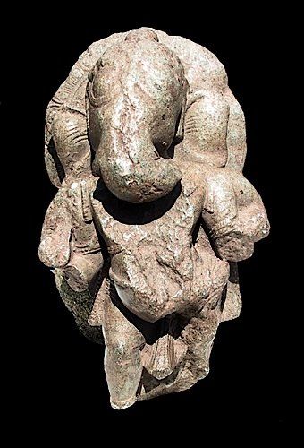  Ganesh à quatre bras, en pierre recouverte d'une patine limoneuse. Manques divers....