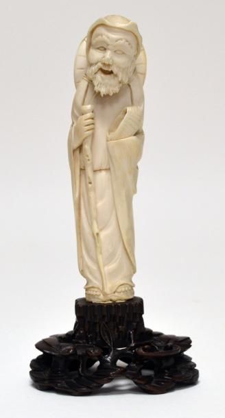 null CHINE - SAGE en ivoire sculpté tenant un bâton et une sébile. Début du XXe....