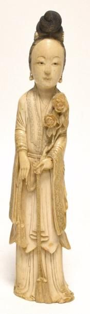 null CHINE. GUANYIN en ivoire sculpté, représentée debout tenant une branchage fleuri...