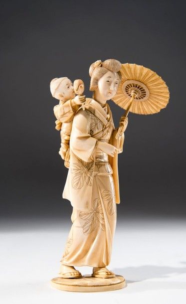 JAPON Sujet en ivoire sculpté, gravé et patiné présentant une femme portant son enfant...