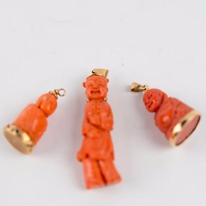 null Lot de trois pendentifs en or jaune et corail: deux bouddhas et un enfant riant....
