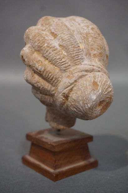 null Female head with a melon-cut hairstyle ending in a bun. Ochre terracotta. Egypt,...