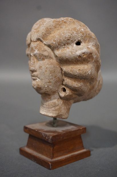 null Female head with a melon-cut hairstyle ending in a bun. Ochre terracotta. Egypt,...