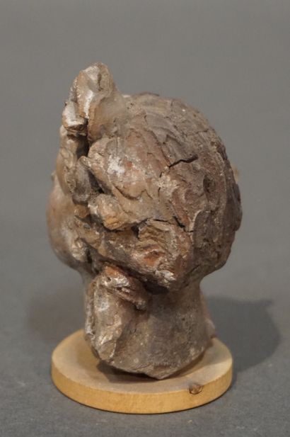 null Female head with hair held by a thick plant crown. Ochre terracotta. Crown partly...