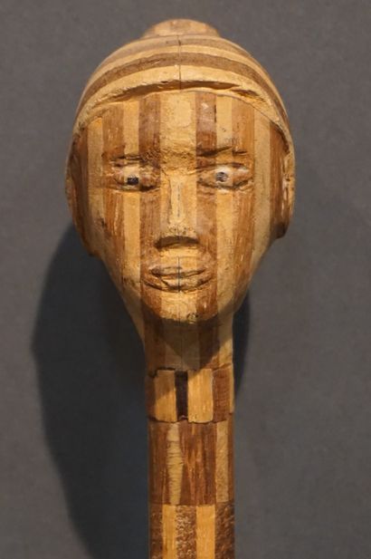 *Canne Canne en bois marqueté bicolore à pommeau sculpté d'une tête de femme. 87,5...