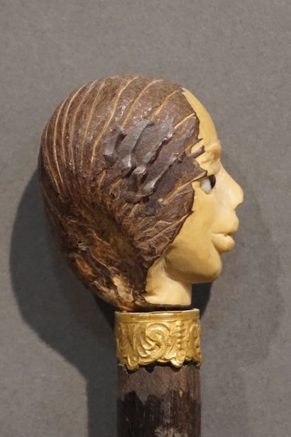 *Canne Canne à pommeau figurant une tête sculptée et bague en métal doré. 88 cm