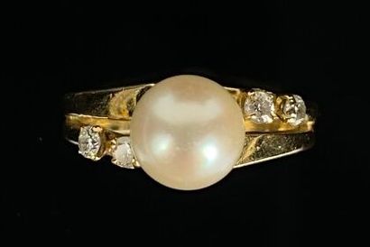 null Bague en or jaune ornée d'une perle centrale, épaulée de quatre petits diamants...