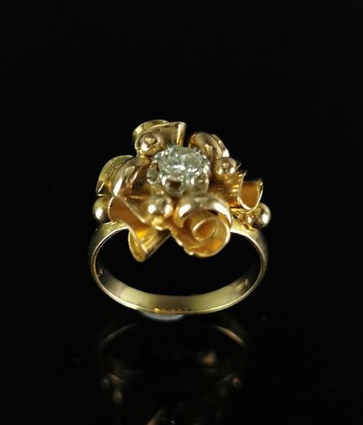 null Bague en or jaune à décor de rubans, ornée en son centre d'un diamant rond pesant...