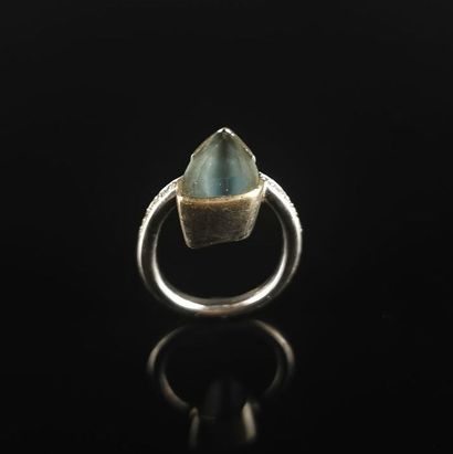 null Bague moderniste en or gris, ornée d'une pierre bleue triangulaire décentrée.
Tour...