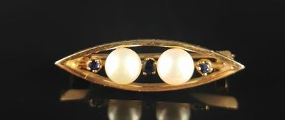 null Broche en or jaune de forme navette sertie de deux perles et trois petits saphirs.
D_...