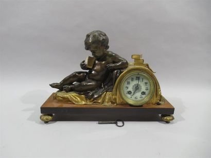 null Bronze clock with double patina showing a putti on a bed reading a book leaning...