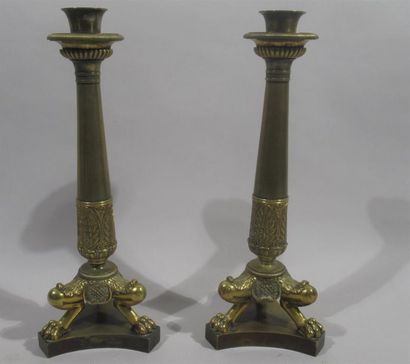 null Pair of bronze candlesticks with gilded patina, resting on a tripod base decorated...