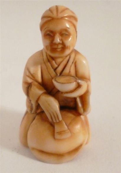 null Netsuke in ivory finely carved by an artist kneeling down and washing a mokugyo...