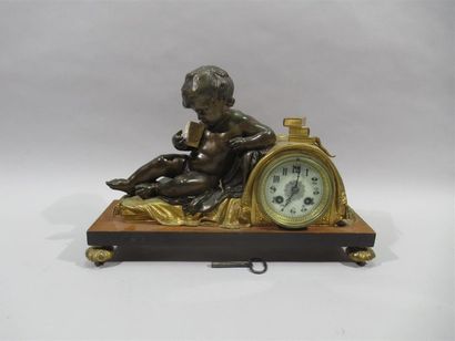 null Bronze clock with double patina representing a putti on a bed reading a book...