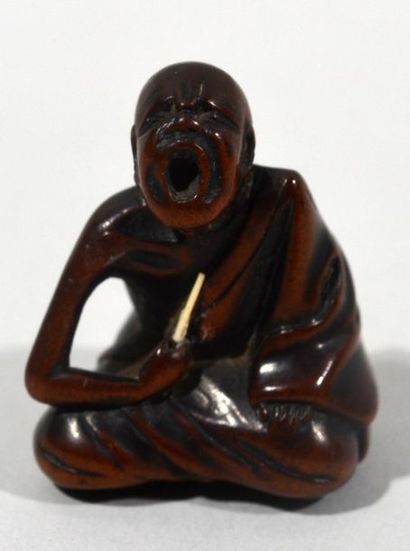 null Netsuke en buis sculpté d'un éternueur public assis, la tête levée et la bouche...