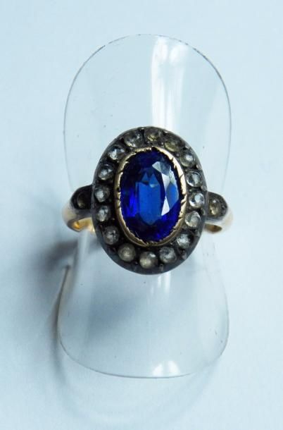 null Bague en métal doré ornée d'une pierre bleue dans un entourage de pierres blanches...