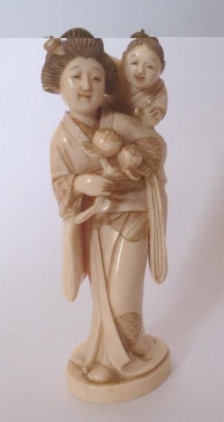 null Okimono en ivoire finement sculpté d'une jeune femme portant son fils qui cherche...