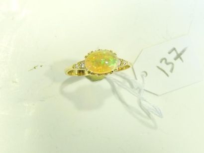 Bague en or jaune centrée d'un cabochon d'opale épaulé de diamants taille brillant....