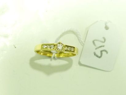 Bague en or jaune 18K (750/oo) centrée d'un diamant taille brillant épaulé de lignes...