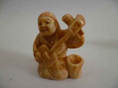 null Netsuke en ivoire bien sculpté et patiné d'un souriant joueur de shamisen agenouillé...