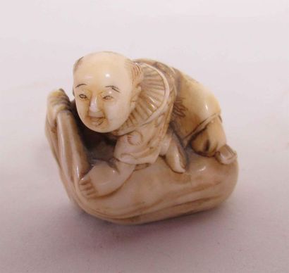 null Netsuke en ivoire finement sculpté d'un souriant Karako allongé sur un sac de...