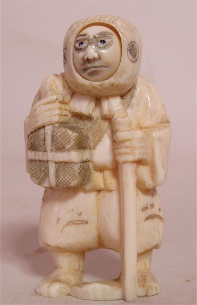 null Netsuke en ivoire sculpté en forme de voyageur à la tête mobile tenant des paquets...