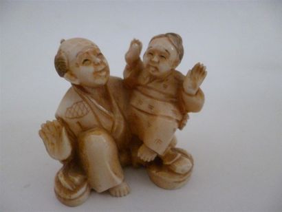 null Netsuke en ivoire finement sculpté d'un père assis tenant son fils assis sur...