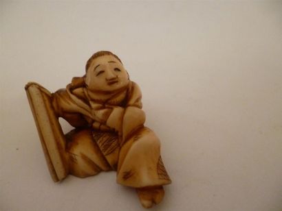 null Netsuke en ivoire bien sculpté et à belle patine d’un enfant assis, un sac de...