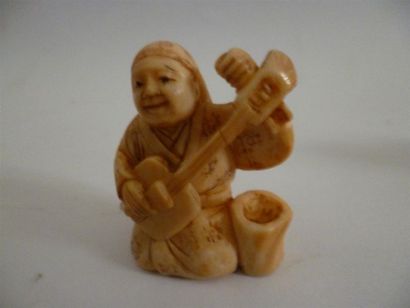 null Netsuke en ivoire bien sculpté et patiné d’un souriant joueur de shamisen agenouillé...