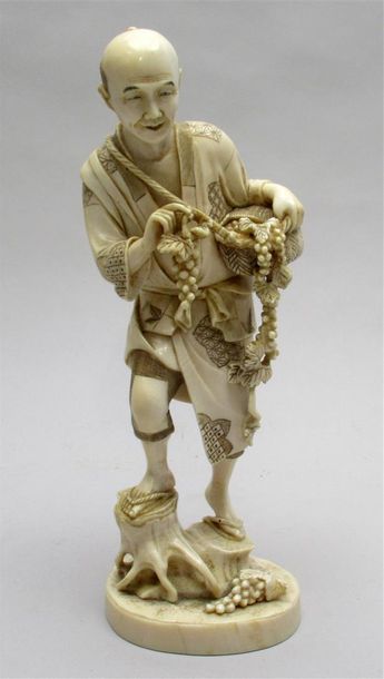 null Okimono en ivoire sculpté figurant un homme récoltant des grappes de raisins...