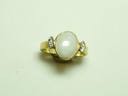 null Bague en or jaune 18K (750/oo) centrée d'un cabochon d'opale épaulé par 3 diamants...