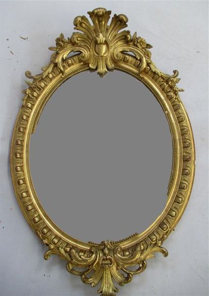 null Miroir ovale, le cadre en bois mouluré et sculpté, stuqué et doré à décor de...