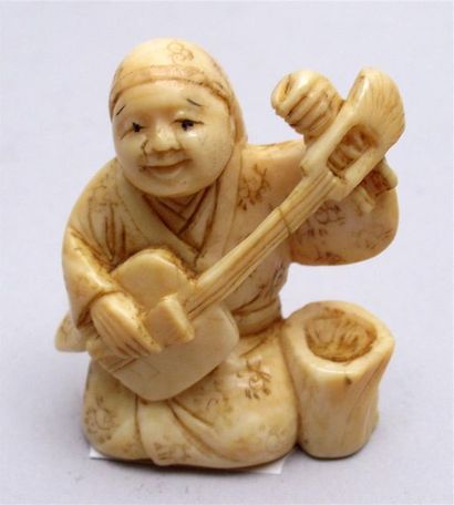 null Netsuke en ivoire bien sculpté et patiné d’un souriant joueur de shamisen agenouillé...