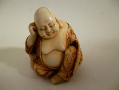 null Okimono en ivoire sculpté d’un souriant bouddha assis, endormi tenant sa tête...