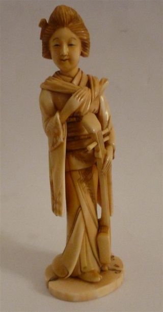 Okimono en ivoire finement sculpté d'une jeune musicienne en kimono d'apparat Jouant...