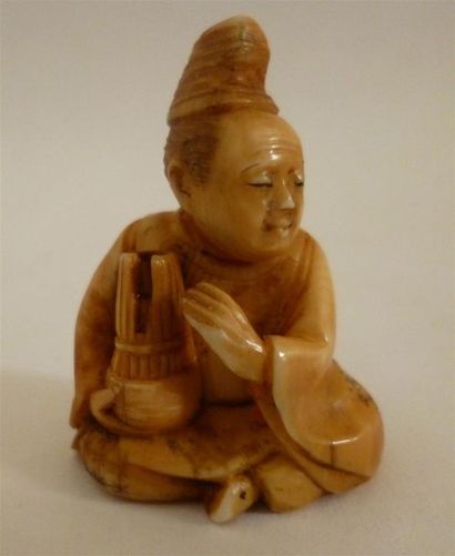 Beau Netsuke en ivoire finement sculpté et patiné d'un musicien assis tenant une...