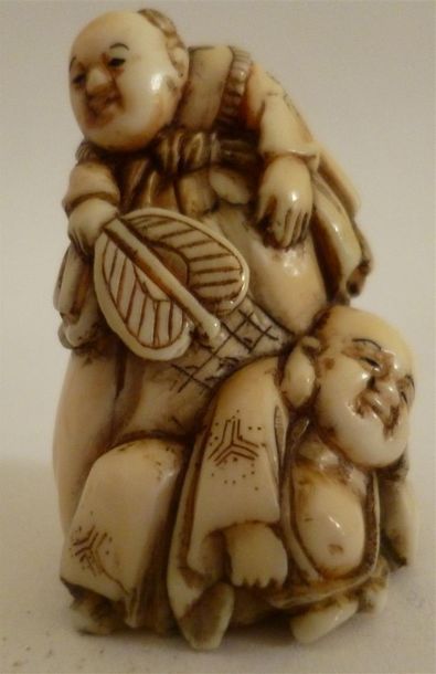 Netsuke en ivoire bien sculpté de deux enfants dont l'un tient un ushiwa (éventail...