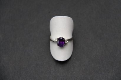 null Bague en or gris 18K (750/oo) ornée d'une améthyste ovale épaulée par deux diamants...