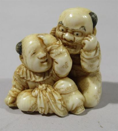 null Netsuke en ivoire finement sculpté de deux enfants jouant avec un masque pour...