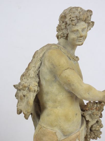 null A terracotta BACCHUS BUST resting on a marble base in the form of a fluted column,...